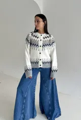 Cardigan de punto con diseño jacquard de inspiración nórdica, en tonos blanco, gris y marrón. Presenta cuello redondo, cierre frontal con botones y mangas largas con puños acanalados.