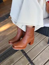 Bota de caña media color óxido, confeccionada en cuero, con plataforma y taco cuadrado texturizado, punta cuadrada y cierre lateral.