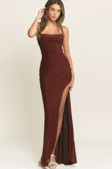 Vestido largo de fiesta confeccionado en tela lurex color bordó. Presenta un escote recto con breteles finos, corte ajustado al cuerpo y una abertura lateral profunda en la falda.