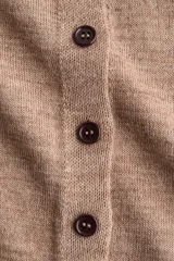 Saco en punto fino color tostado con cuello alto, hombros caídos y cierre frontal de botones. Cuenta con ribetes acanalados en los puños y el bajo.