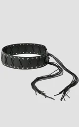 Cinto tipo faja de cuero sintético negro, con diseño de cordones cruzados y ojalillos metálicos plateados. Presenta un extremo con flecos largos decorativos.