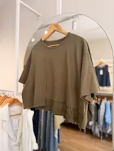 Remera verde militar de calce oversize, cuello redondo y manga corta, con detalle de puntilla bordada en el ruedo inferior.