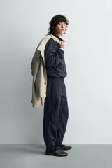 Chaqueta de corte relajado, color azul marino oscuro, confeccionada en tejido técnico ligero. Presenta cuello subido, forro interior de malla, bolsillos de vivo en cadera y bajo ajustable con elástico lateral. Cierre frontal con cremallera de doble dirección.