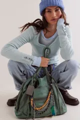 Bolso tote de cuero lavado negro con efecto gastado, interior amplio, bolsillos exteriores con cremallera, dos asas de mano y correa desmontable y regulable.