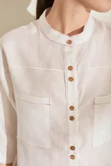 Camisa de lino color fucsia, con cuello mao, mangas cortas holgadas y cierre frontal con botones de madera. Cuenta con bolsillos frontales en el pecho.