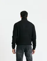 Sweater de punto inglés color verde, con cuello alto y cierre frontal parcial metálico. Diseño de manga larga con puños y ruedo acanalados.