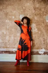 Vestido midi de jersey color naranja con estampado abstracto en negro. Tiene mangas largas abullonadas y escote redondo.