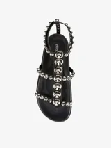 Sandalias planas color blanco con tiras decoradas con tachas plateadas y cierre de velcro.