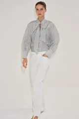 Camisa de viscosa con estampado de lunares pequeños, escote en pico con lazada frontal, manga larga y puños anchos.
