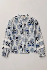 Camisa de manga larga con estampado floral en tonos azules y blancos, cuello con volados y detalles de encaje a lo largo de la botonadura y en las mangas.