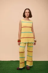 Conjunto de dos piezas de punto acanalado color amarillo, compuesto por un top sin mangas y un pantalón ancho. Ambas prendas tienen franjas decorativas horizontales en color rojo y celeste.