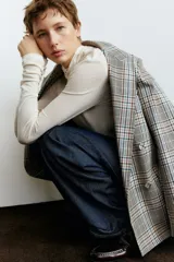 Jean de tiro alto con corte baggy, confeccionado en denim de algodón. Presenta diseño de cinco bolsillos, cierre frontal con botón y silueta de pierna curva con volumen en la cadera.