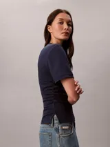 Remera Calvin Klein de manga corta y cuello redondo, color azul marino, confeccionada en algodón pima. Presenta costuras verticales en el frente y un sutil logo gráfico script bordado en color rojo en el pecho.