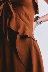 Blusa color camel con tirantes finos, escote en V con volados y cordones para atar en el frente. Presenta diseño tipo capa con parte trasera más larga y caída asimétrica.