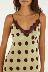 Vestido lencero midi de color verde claro con estampado de lunares marrón oscuro, tirantes finos y detalle de encaje marrón en el escote.