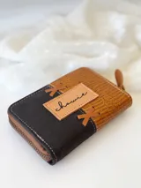 Billetera pequeña de cuero marrón y negro con cierre metálico y monedero interno.