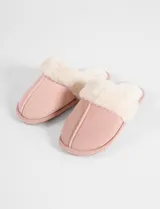 Pantufla tipo mule color tostado con exterior de material suave y forro interior de corderito sintético color crema. Cuenta con suela plana de goma.
