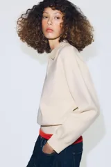 Jersey de punto con cuello tipo polo, manga larga con puños y cierre frontal con botones. Presenta un bolsillo de plastrón en el pecho y diseño de corte holgado.