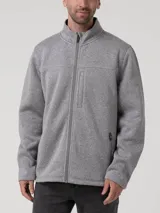 Polar de hombre color gris robusto, con cuello alto y cierre frontal. Presenta un bolsillo vertical con cierre en el pecho y bolsillos laterales con cierre. El tejido es de punto jaspeado.