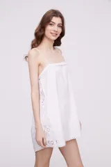 Vestido corto color marfil con breteles finos, escote recto y detalle de puntilla en los laterales y ruedo.