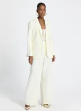 Blazer color blanco roto, de tejido de punto con corte entallado, cuello, dos bolsillos de ribete con solapa, mangas largas con puños abotonados y cierre frontal con botones.