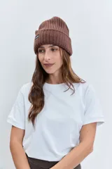Gorro tipo beanie de punto grueso color amarillo pastel, con vuelta en el borde y etiqueta pequeña con logo en el frente.