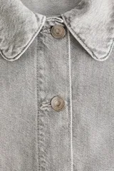Campera corta en denim de algodón con cuello, cierre frontal de botones y bolsillos de parche delanteros.