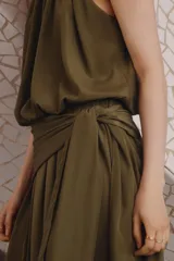 Pantalón globo de tiro alto color verde militar en tejido satinado con leve brillo. Presenta cintura elástica revestida, sección cruzada que se ata en un lateral con caída fluida y bajos elásticos ajustados.
