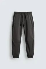 Pantalón tipo jogger de corte slim fit, confeccionado en tejido de algodón con elasticidad. Presenta cintura elástica ajustable con cordón, bolsillos frontales, bolsillos traseros de vivo y bajos con puños elásticos.