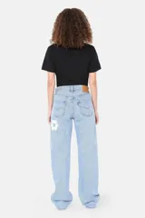 Pantalón de jean celeste con apliques florales geométricos en tonos azules y blancos.