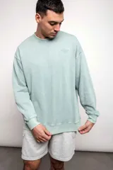 Buzo verde agua liso, de corte oversize, confeccionado con 60% algodón y 40% poliéster.