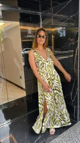 Vestido largo estampado con escote en V profundo y tirantes anchos. El diseño presenta un frunce o nudo en el centro del busto y tajos laterales en la falda.