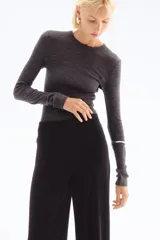 Pantalón negro de tiro alto, corte ancho y largo midi. Confeccionado en tejido de punto elástico con costuras verticales en el frente.