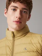 Chaleco inflable color ocre con cierre frontal y cuello alto. Tiene el logo de la marca bordado en el pecho.