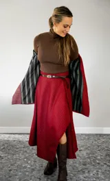 Pollera midi de corte irregular con diseño de estampado cuadrillé en tonos rojo y negro. Presenta un acabado con flecos en el borde y una abertura lateral que deja ver la pierna.