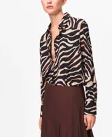 Camisa de poliéster con estampado animal print tipo cebra en tonos negro, marrón y beige, manga larga y cuello camisero clásico.