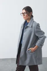 Tapado corto de paño color marrón, con diseño recto, cuello camisero y cierre frontal con broches metálicos. Cuenta con bolsillos frontales.