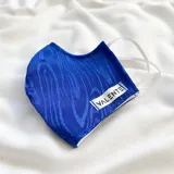Tapabocas de tela azul con diseño de líneas onduladas y etiqueta blanca con la marca "Valente".