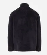 Buzo de tejido peludo color negro, con cuello alto y cierre frontal parcial. Presenta mangas largas con puños elásticos, bolsillo tipo canguro y etiqueta decorativa en el pecho.