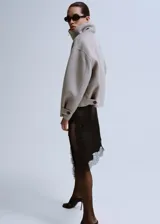 Falda midi asimétrica de satén negro, con detalles de encaje floral en el dobladillo y diseño fluido.