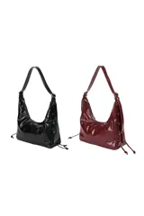 Cartera tipo hobo de material sintético con acabado brillante, diseño estructurado con laterales decorados con cordones y herrajes metálicos. Cuenta con cierre superior con cremallera y correa de hombro ajustable.