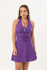 Vestido corto violeta con escote halter, frunces en la cintura y falda acampanada. Espalda abierta con sujeción en el cuello. Confeccionado en lino imperial liso.