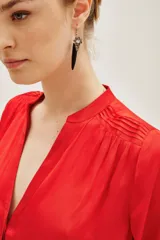 Camisa de satén color rojo, con cuello mao y escote en V, mangas largas con puños elásticos y detalle de frunces en los hombros.