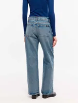 Jean de denim 100% algodón con lavado medio de aspecto vintage, tiro medio y corte flare con perneras ligeramente acampanadas.