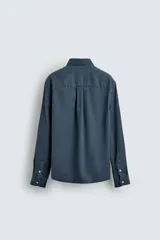 Camisa de corte relajado confeccionada en una mezcla de lyocell y algodón con efecto lavado. Presenta cuello solapa, manga larga con puños abotonados, bolsillo de plastrón en el pecho y cierre frontal con botones.