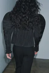 Blusa negra de cuello alto y manga larga abullonada con puños abotonados. Tejido arrugado y cierre frontal oculto con botones. Zara Woman Collection.