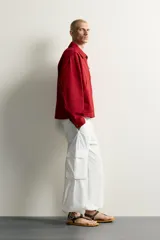 Cazadora relaxed fit de Zara confeccionada en tejido de algodón rojo con efecto lavado. Presenta cuello solapa, manga larga, bolsillos de plastrón en la cadera y cierre frontal de cremallera oculta con solapa y alamares metálicos.
