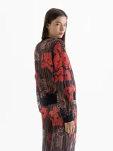 Buzo de punto calado con estampado full print en tonos rojos, marrones y negros. Presenta mangas amplias y terminaciones en cuello, puños y cintura en tela negra que genera contraste.