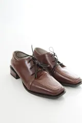 Zapato de charol negro de cuero vacuno con textura grabada tipo reptil, punta cuadrada y cordones al tono.