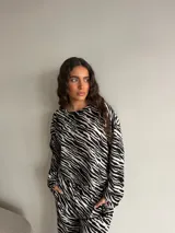 Remera manga larga de viscosa con estampado animal print tipo cebra en blanco y negro, corte holgado y cuello redondo. Presenta un pequeño parche cuadrado bordado en el pecho.
